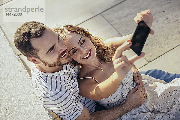 Lächelndes Paar  das sich mit einem Smartphone selbstständig macht