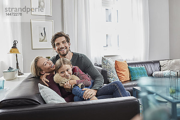 Porträt einer glücklichen Familie  die zu Hause auf der Couch sitzt