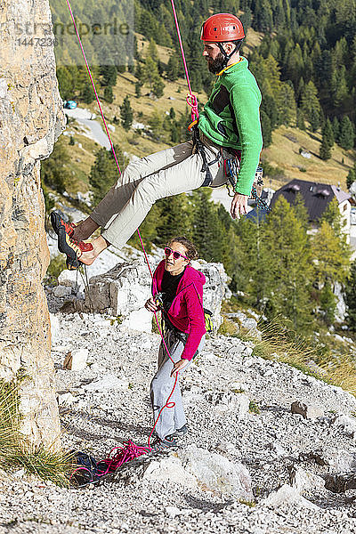 Italien  Cortina d'Ampezzo  Mann seilt sich mit Hilfe einer Frau in den Dolomiten ab