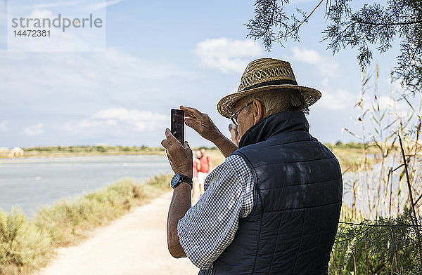 Italien  Sizilien  Naturschutzgebiet Vendicari  älterer Mann beim Fotografieren mit einem Smartphone