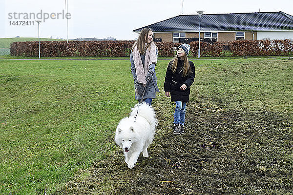 Zwei Schwestern beim Spaziergang mit Hund