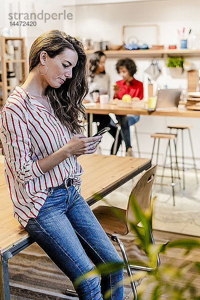 Frau mit Handy bei Tisch