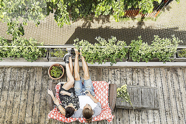 Junges Paar entspannt sich im Sommer auf ihrem Balkon und trinkt Kaffee