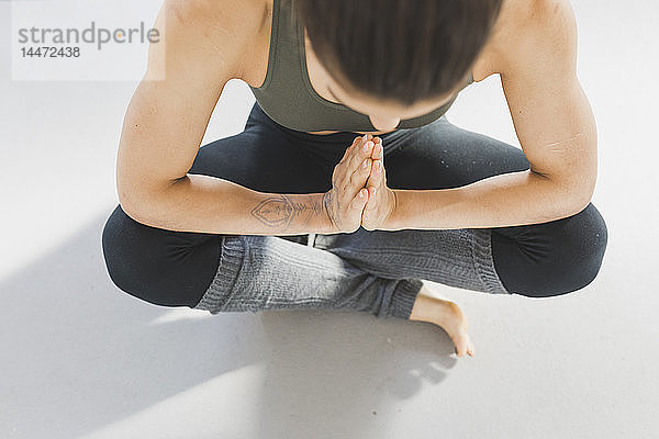 Draufsicht einer Frau  die auf dem Boden sitzt und Yoga praktiziert