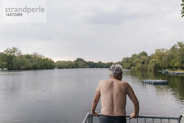 Älterer Mann steht an einem See