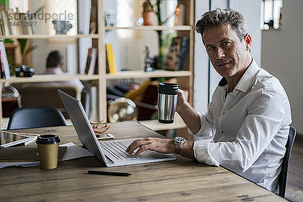 Porträt eines Geschäftsmannes mit Laptop am Schreibtisch