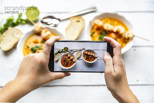 Mädchen fotografiert Schüsseln mit Süßkartoffelsuppe mit einem Smartphone  Nahaufnahme
