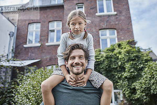 Porträt eines glücklichen Vaters mit Tochter im Garten ihres Hauses