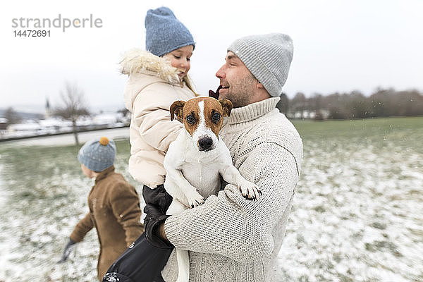 Vater mit zwei Kindern und Hund in Winterlandschaft