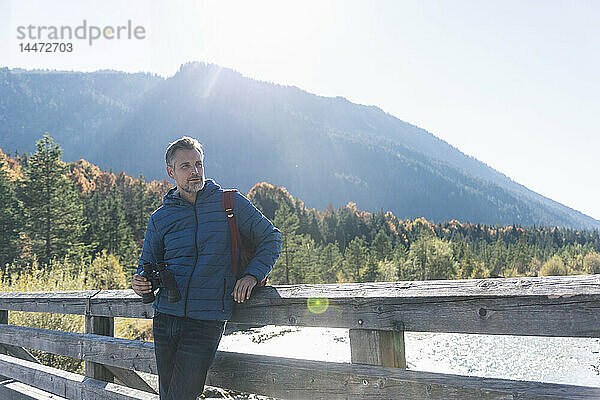 Österreich  Alpen  Mann auf Wanderung mit Fernglas auf einer Brücke stehend