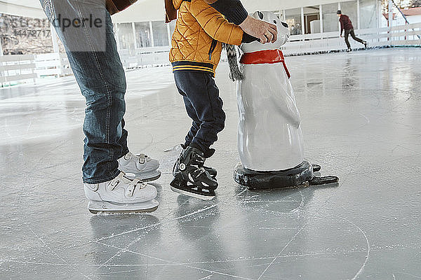 Grossvater und Enkel auf der Eisbahn  Schlittschuhlaufen  mit Eisbärenfigur als Requisite