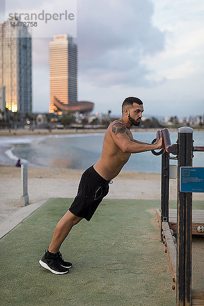 Barbusiger  muskulöser Mann beim Training am Strand