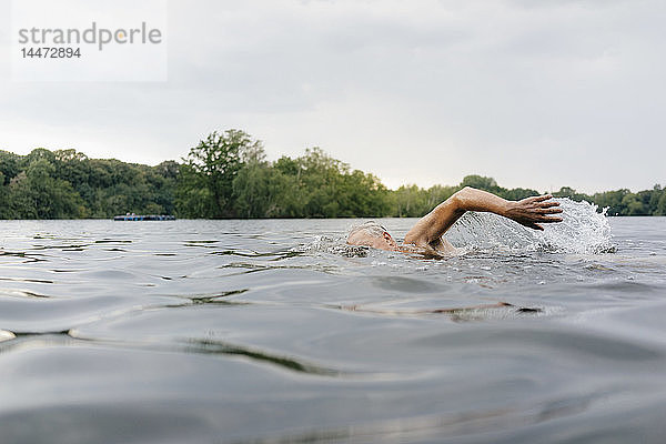 Älterer Mann schwimmt in einem See