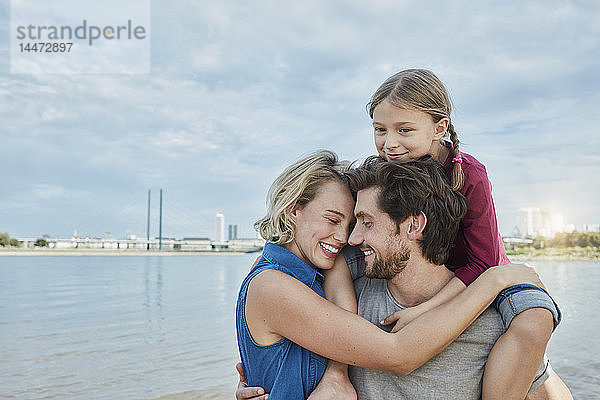 Deutschland  Düsseldorf  glückliche Familie mit Tochter am Rheinufer umarmt