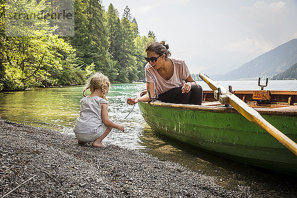 Österreich  Kärnten  Weissensee  Mutter im Ruderboot mit Tochter am Seeufer