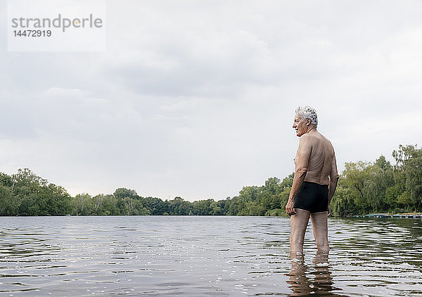 Älterer Mann steht in einem See