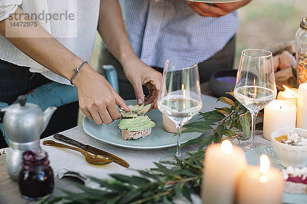 Nahaufnahme eines Paares  das im Freien ein romantisches Essen bei Kerzenlicht zubereitet