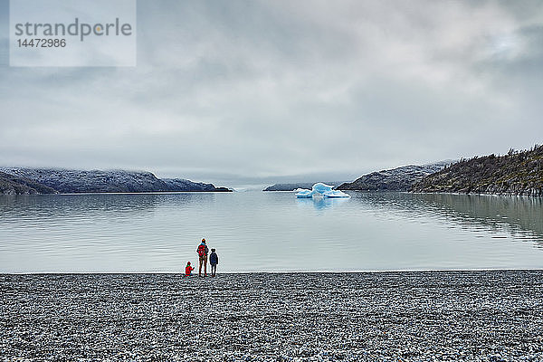 Chile  Torres del Paine Nationalpark  Lago Grey  Frau mit zwei Söhnen steht am Ufer und schaut auf einen Eisberg