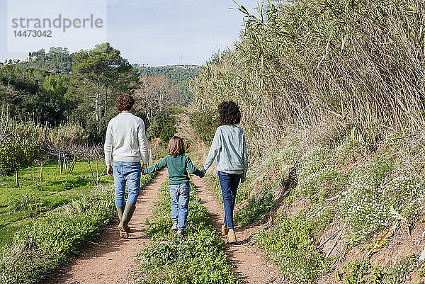 Glückliche Familie beim Spaziergang auf dem Land  Händchen haltend