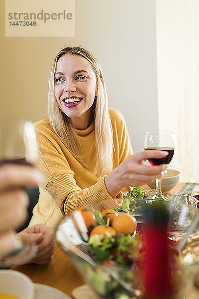 Junge Frau trinkt Rotwein ata Mittagessen mit Freunden