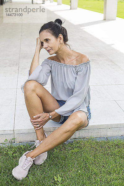 Porträt einer reifen Frau  die im Sommer auf der Terrasse sitzt