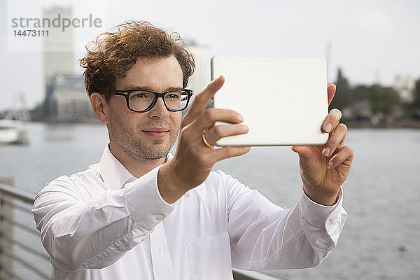 Deutschland  Berlin  Porträt eines Geschäftsmannes  der mit einem digitalen Tablett fotografiert