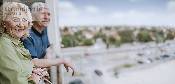 Lächelndes älteres Paar auf dem Balkon mit Blick auf die Aussicht