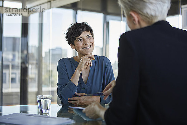 Zwei Geschäftsfrauen unterhalten sich am Schreibtisch im Büro