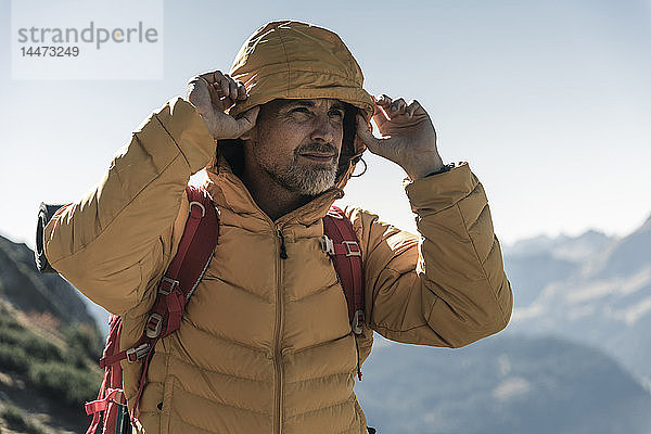 Österreich  Tirol  Porträt eines Mannes mit Kapuzenjacke auf einer Wanderung in den Bergen