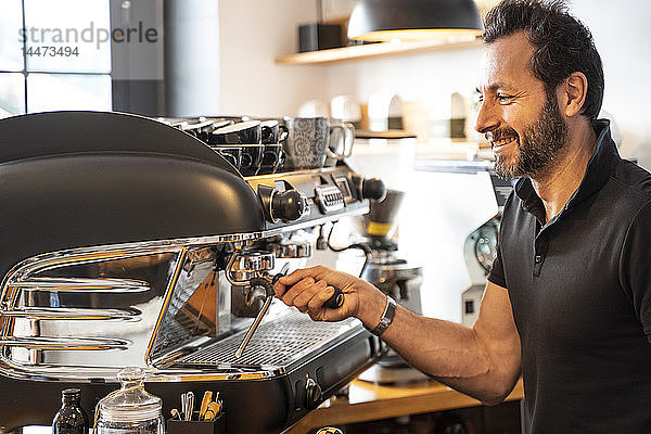Lächelnder Barista bei der Kaffeezubereitung in einem Café