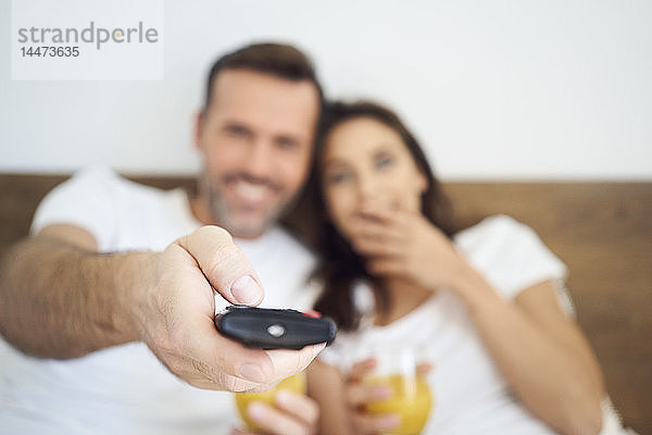 Glückliches Paar beim Fernsehen im Bett