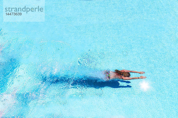 Frau taucht im Schwimmbad unter Wasser