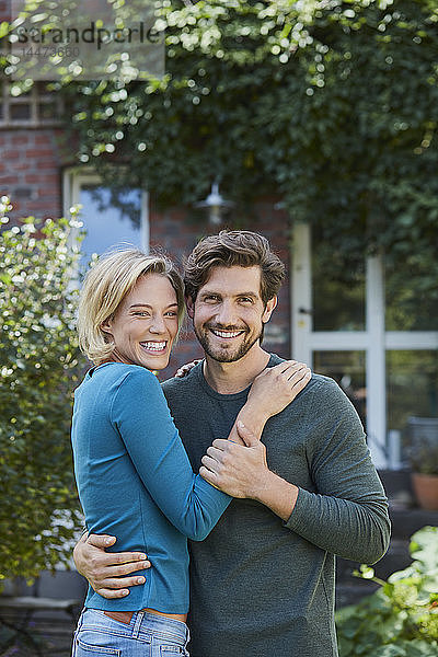 Porträt eines glücklichen Paares im Garten ihres Hauses
