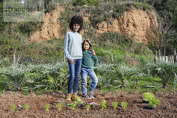 Mutter und Sohn stehen im Gemüsegarten mit Salatsetzlingen