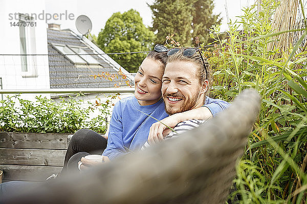 Junges Paar entspannt sich auf dem Balkon  auf der Couch sitzend