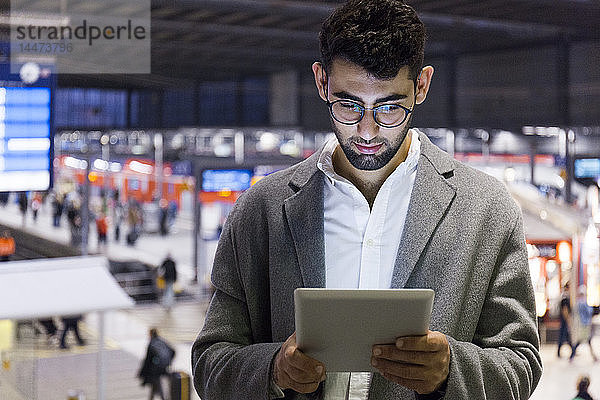 Deutschland  München  junger Geschäftsmann mit digitalem Tablet am Hauptbahnhof