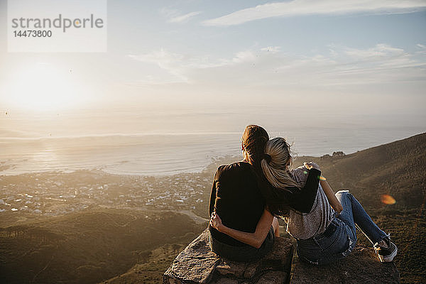 Südafrika  Kapstadt  Kloof Nek  zwei Frauen sitzen bei Sonnenuntergang auf einem Felsen