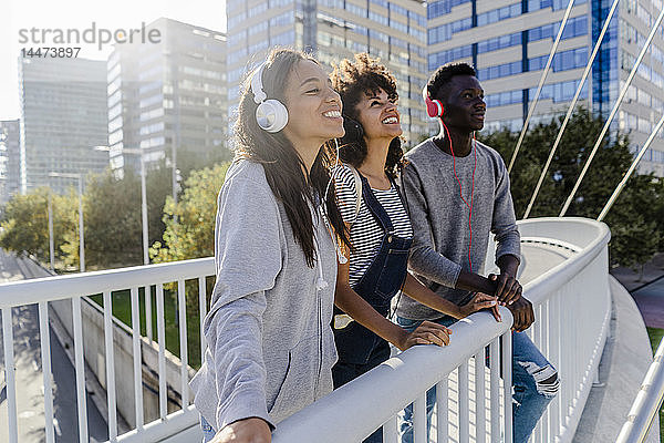 Freunde stehen auf einer Brücke  haben Spaß  hören Musik