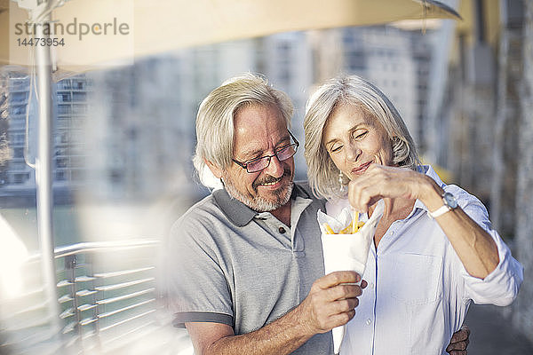 Älteres Ehepaar macht eine Städtereise  isst Pommes Frites