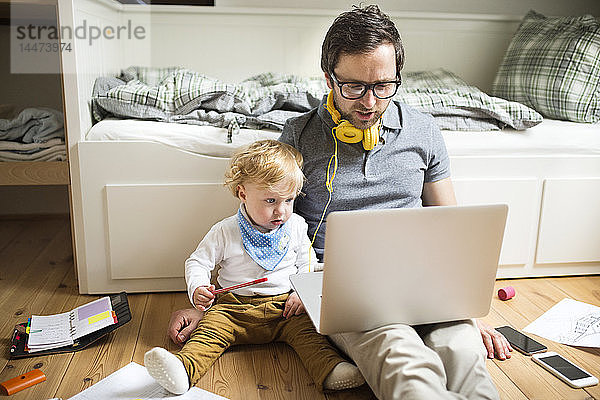 Vater zu Hause mit seinem kleinen Sohn und Laptop