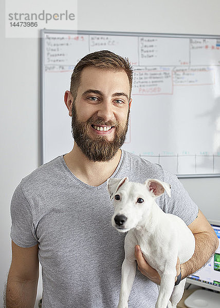 Porträt eines lächelnden Mannes im Büro mit seinem Hund