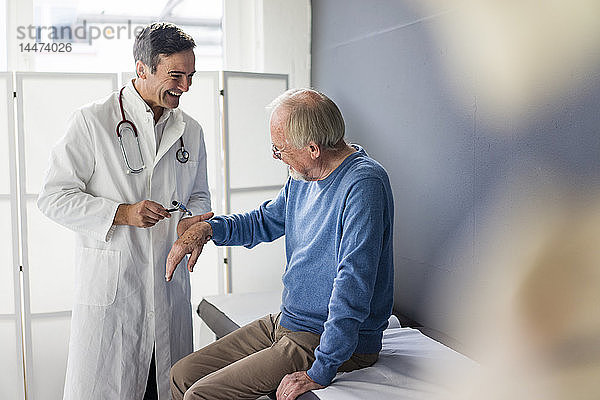 Glücklicher Arzt untersucht älteren Patienten in medizinischer Praxis