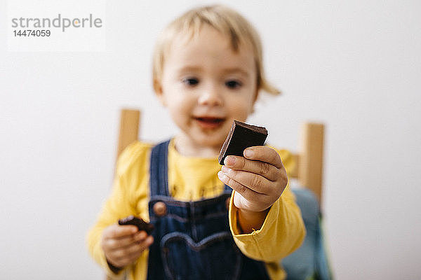 Hand eines lächelnden Kleinkindes mit einem Stück Schokolade in der Hand  Nahaufnahme
