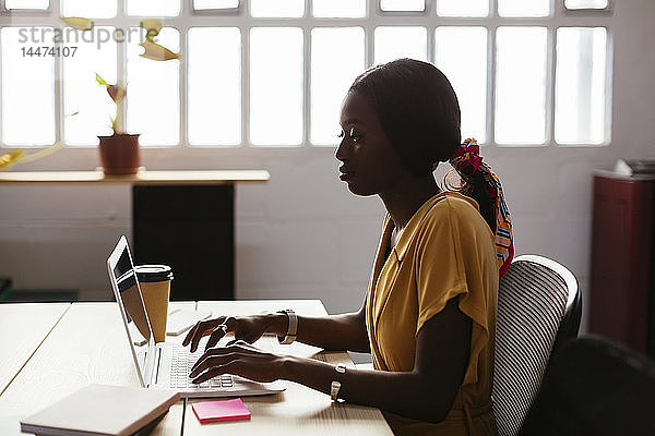 Junge Frau mit Laptop am Schreibtisch im Büro