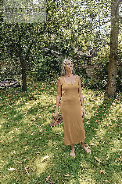 Frau steht barfuss im Garten und entspannt