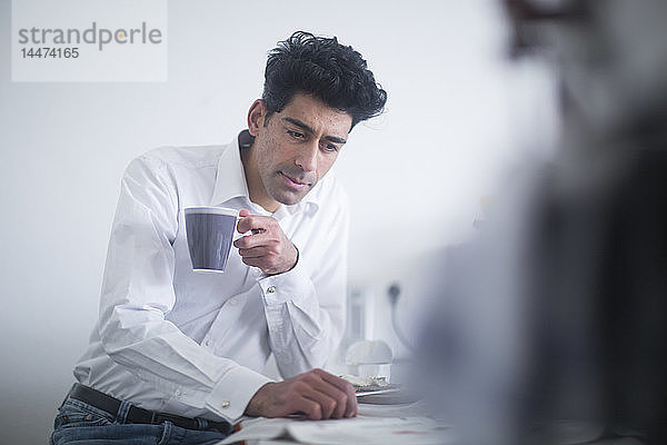 Porträt eines Geschäftsmannes  der morgens zu Hause Kaffee trinkt und Zeitung liest