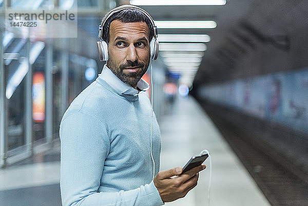 Geschäftsmann benutzt Smartphone an der U-Bahn-Station