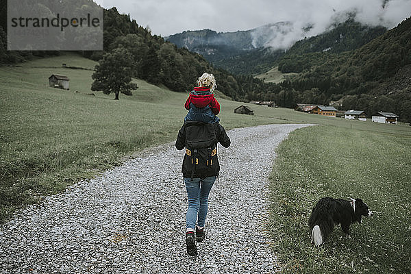Österreich  Vorarlberg  Mellau  Mutter trägt Kleinkind auf den Schultern bei einem Ausflug in die Berge