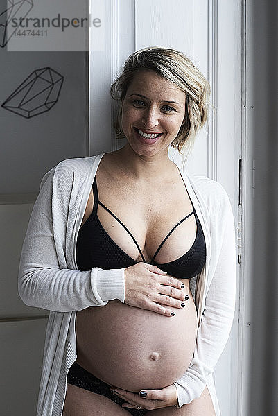 Porträt einer lächelnden  blonden  schwangeren Frau zu Hause