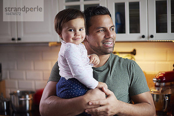 Lächelnder Vater hält Mädchen zu Hause in der Küche